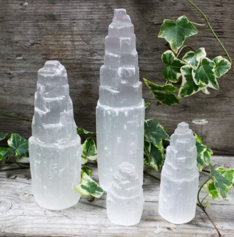 Three crystal towers on a wooden surface with green leaves in the background