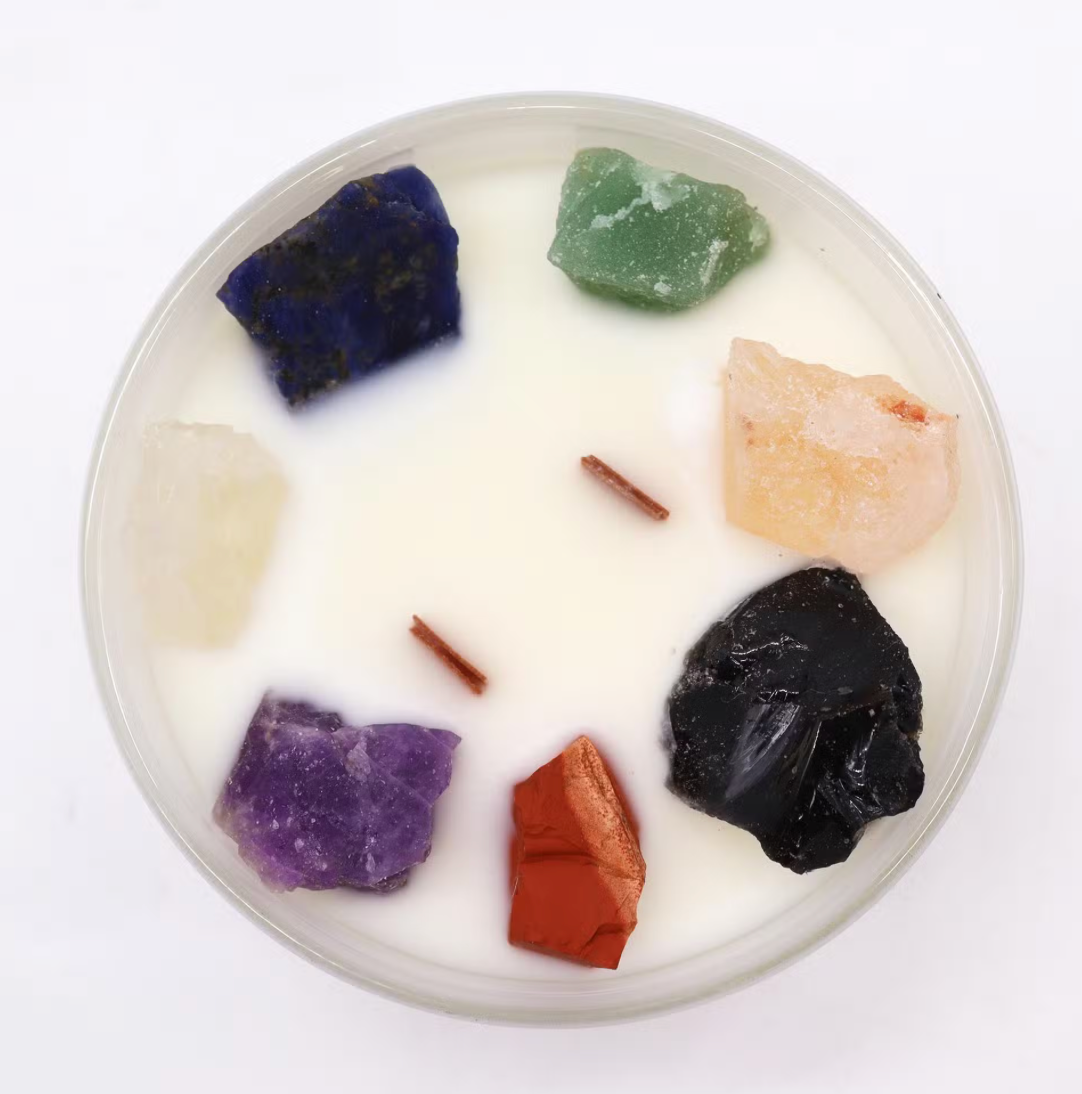 Candle with embedded colorful stones on a white background