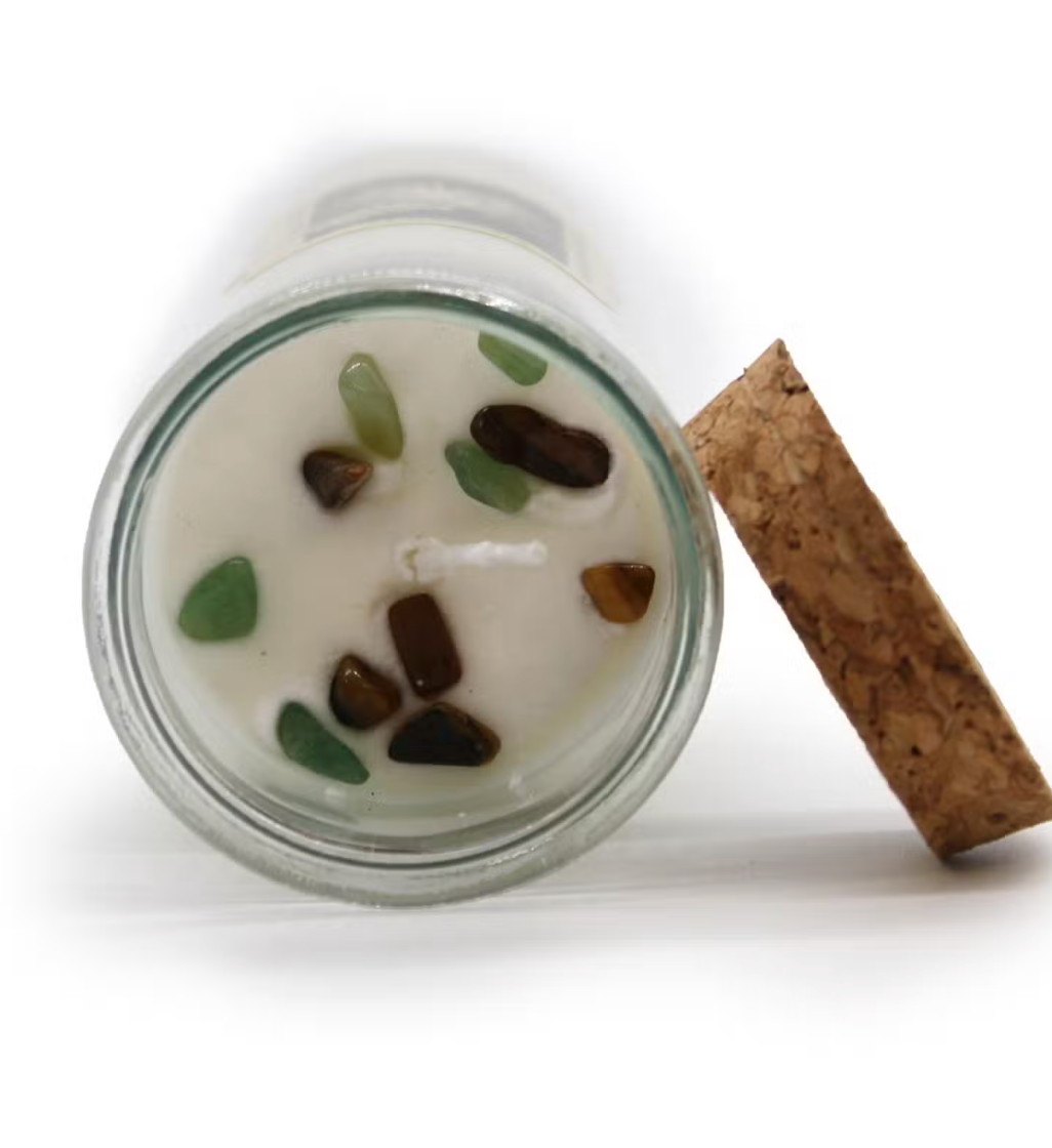 Candle in a glass jar with decorative stones and a cork lid on a white background