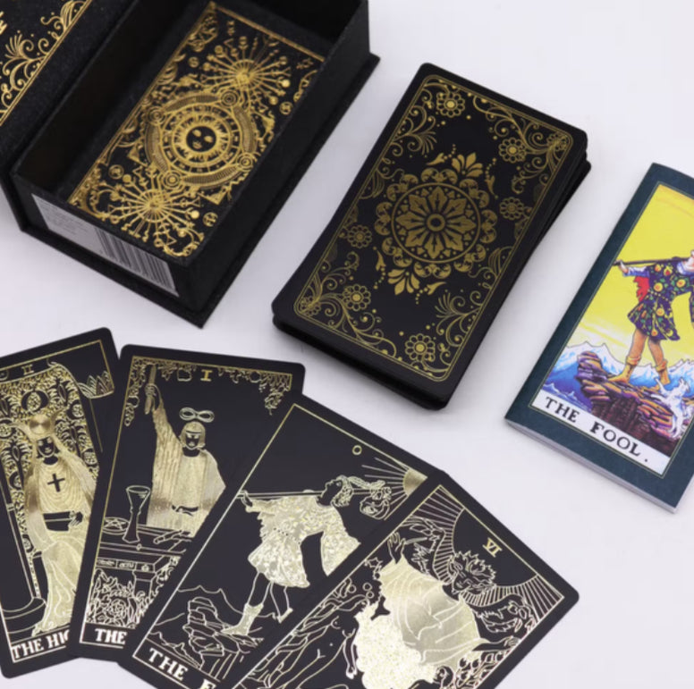Gold foil tarot card deck with guidebook, featuring intricate designs and elegant black and gold packaging