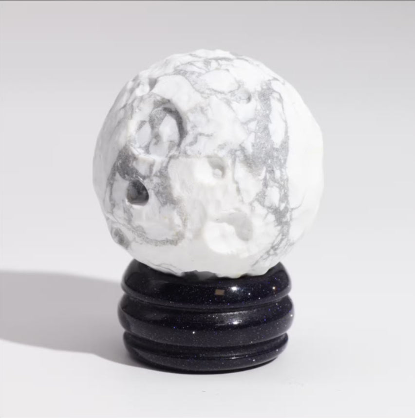 Marble-textured sphere on a black stand against a light gray background