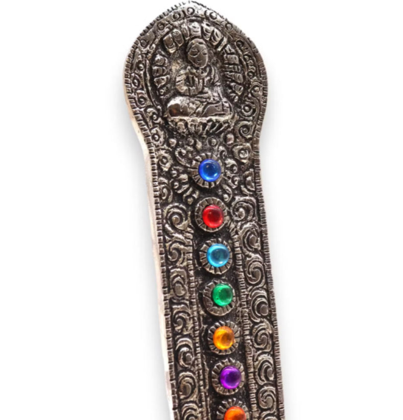 A close up view of the engraved patterns and colorful gemstones on a white background
