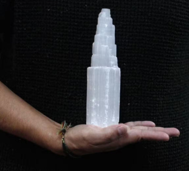 Crystal tower held in a hand against a black background