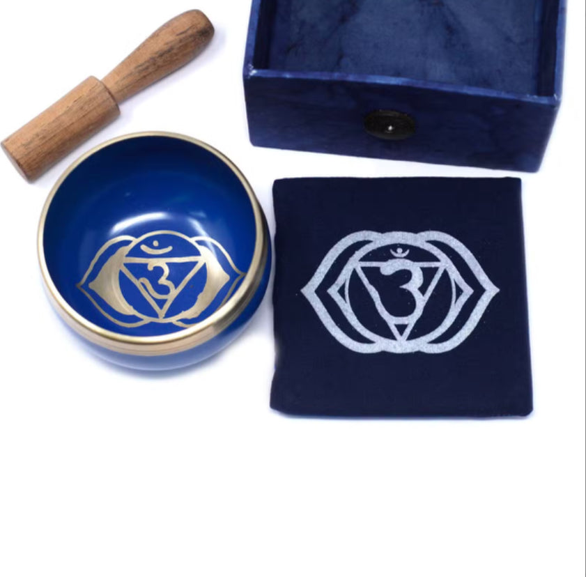 Blue bowl with a white symbol, wooden tool, and matching blue pouch on a white background