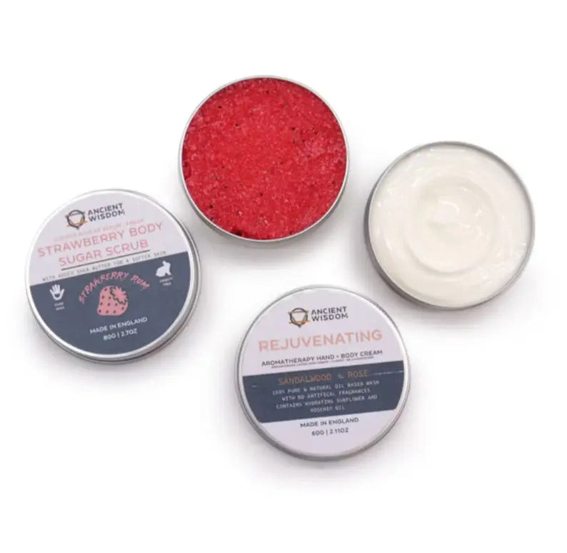 Three containers of Ancient Wisdom products including a red scrub, a white cream, and a blue container on a white background.